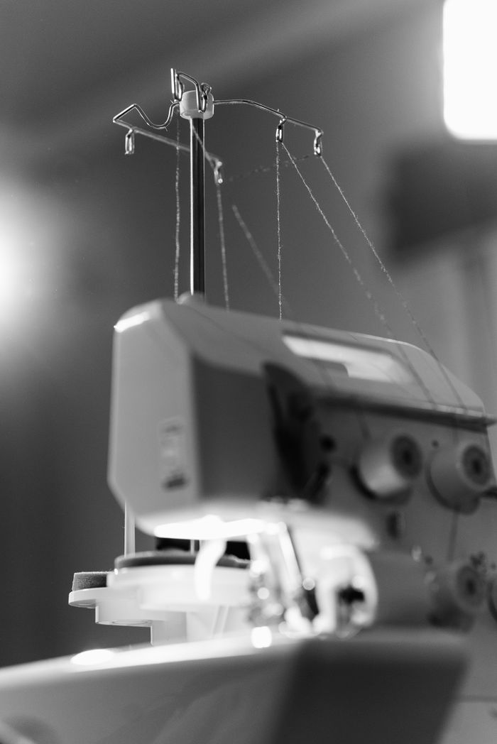 Black and white close-up shot of an industrial sewing machine with threads.